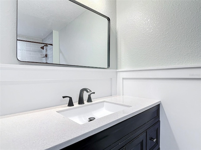 bathroom with vanity, tiled shower, and a textured ceiling