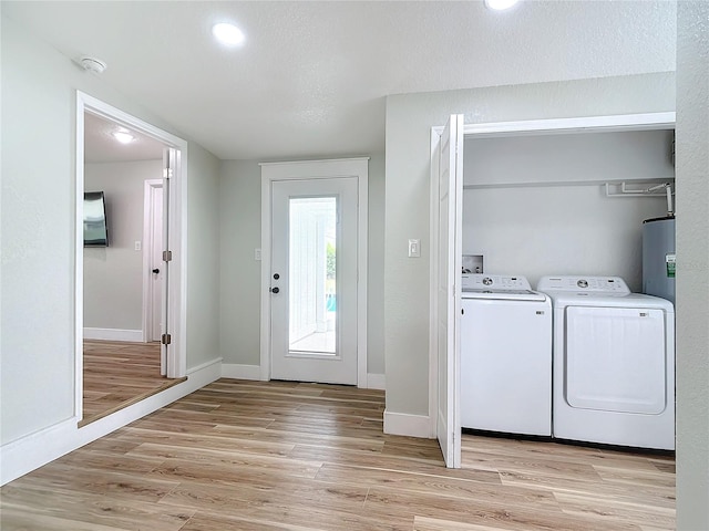 washroom featuring independent washer and dryer, light hardwood / wood-style floors, and water heater