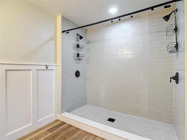 bathroom with hardwood / wood-style floors, a textured ceiling, and a tile shower