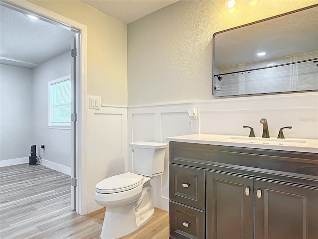 bathroom featuring vanity, hardwood / wood-style flooring, a textured ceiling, and toilet