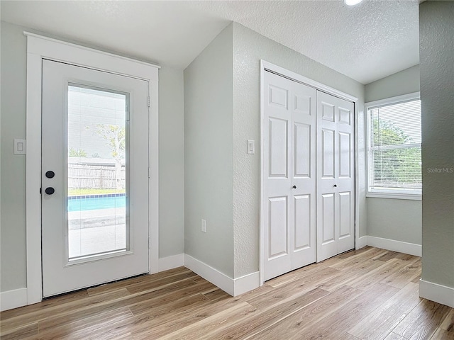 doorway to outside with light hardwood / wood-style flooring and a textured ceiling