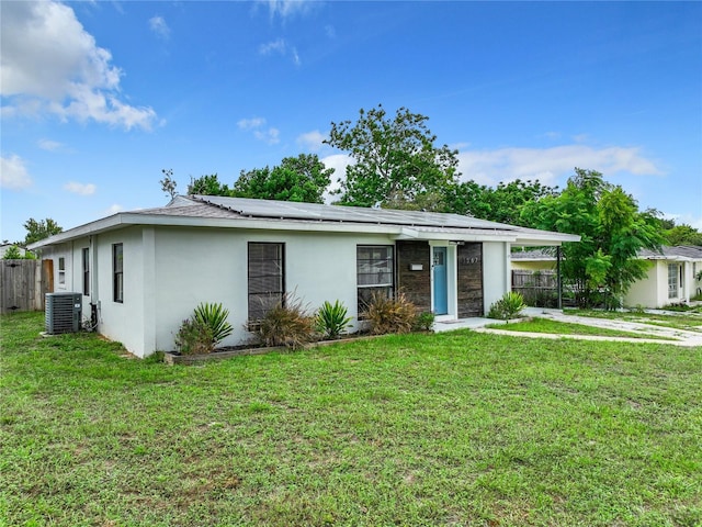 ranch-style home with central AC unit, a front lawn, and solar panels