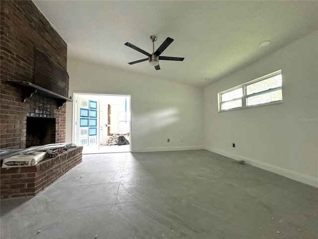 unfurnished living room with lofted ceiling, ceiling fan, a fireplace, and plenty of natural light