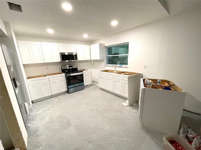 kitchen with appliances with stainless steel finishes, white cabinetry, and sink