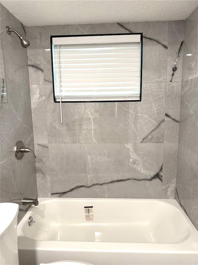 bathroom featuring shower / bath combination, toilet, and a textured ceiling