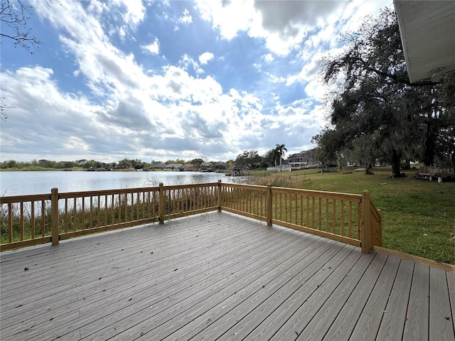 wooden deck with a water view and a lawn