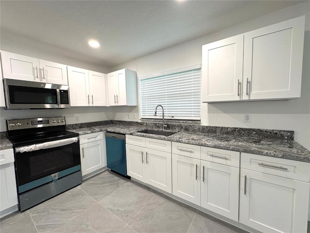 kitchen with white cabinets, appliances with stainless steel finishes, dark stone countertops, a sink, and recessed lighting