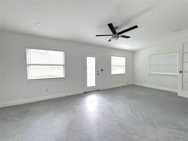 empty room with a textured ceiling, baseboards, and a ceiling fan