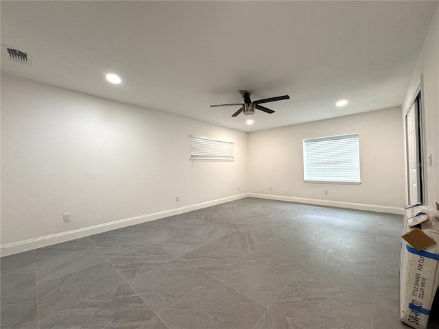 empty room featuring ceiling fan, visible vents, and baseboards