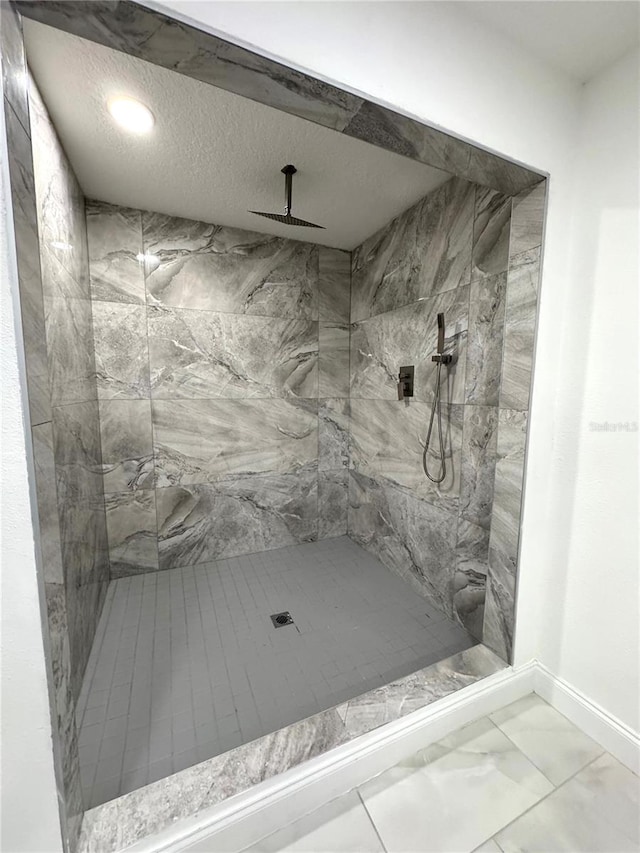 full bath with marble finish floor, baseboards, a textured ceiling, and a marble finish shower