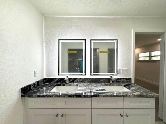 bathroom featuring double vanity, a sink, and a textured wall