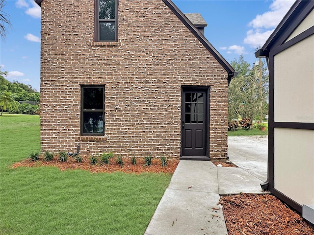 doorway to property featuring brick siding and a yard