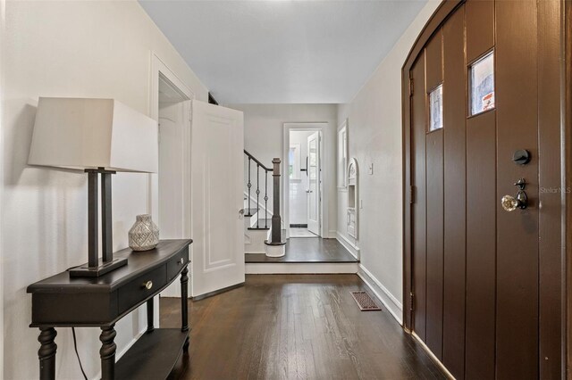 entryway with dark wood-style floors, visible vents, baseboards, and stairs