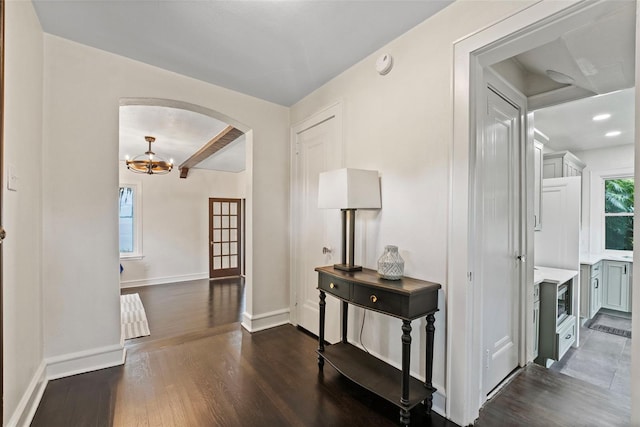 corridor with beamed ceiling, an inviting chandelier, and dark hardwood / wood-style floors