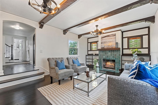 living room with beamed ceiling, a fireplace, wood-type flooring, and a chandelier