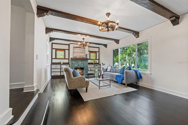 living area with baseboards, dark wood finished floors, a tile fireplace, a chandelier, and beam ceiling