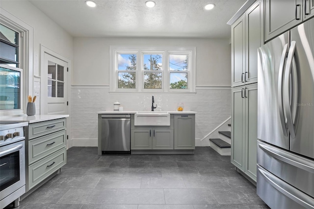 kitchen featuring a sink, stainless steel appliances, light countertops, and wainscoting