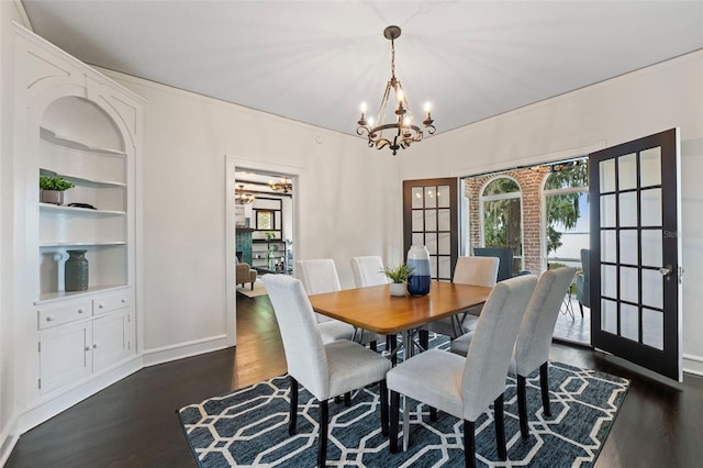 dining space with built in features, dark wood-style flooring, a chandelier, and baseboards