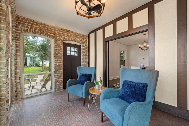 sitting room with brick wall and a notable chandelier