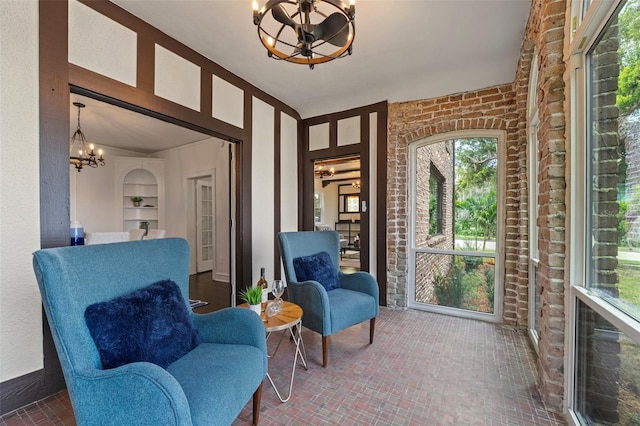 sitting room featuring brick floor, brick wall, and an inviting chandelier