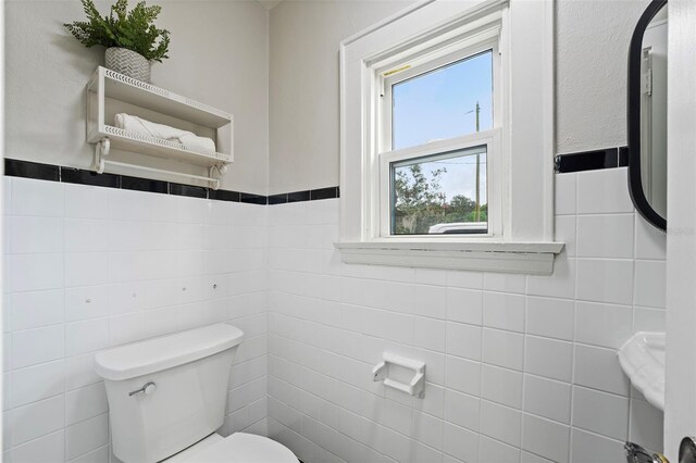 bathroom featuring tile walls and toilet