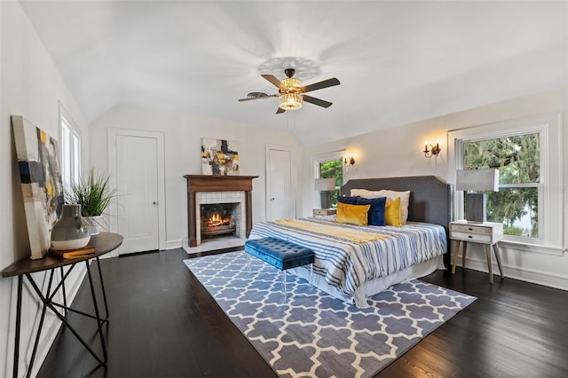 bedroom with ceiling fan, a fireplace, dark hardwood / wood-style flooring, and lofted ceiling