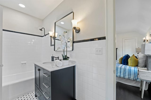 full bath featuring recessed lighting, tile walls, vanity, and bathing tub / shower combination