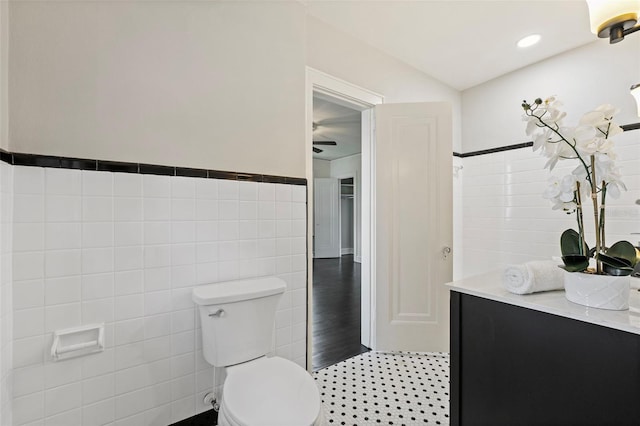 bathroom featuring wainscoting, toilet, tile patterned floors, vanity, and tile walls