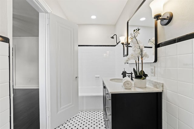 full bathroom featuring a shower, vanity, tile walls, and recessed lighting