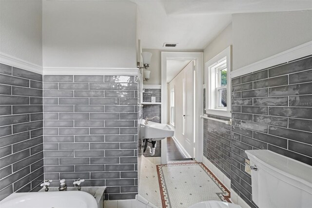 bathroom with sink, tile walls, and toilet