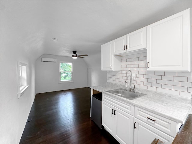 kitchen featuring ceiling fan, white cabinets, a wall unit AC, sink, and dark wood-type flooring