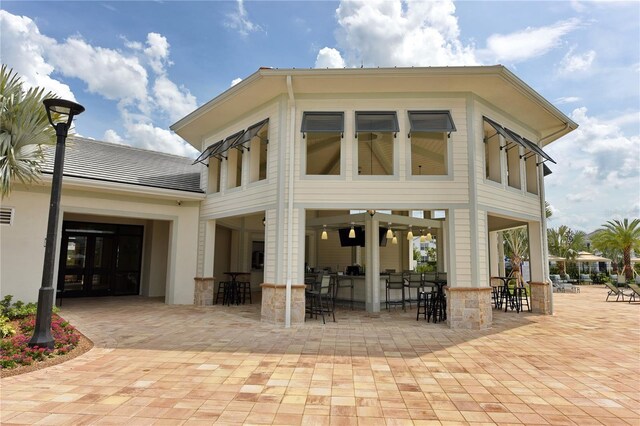 rear view of property featuring a patio and an outdoor bar