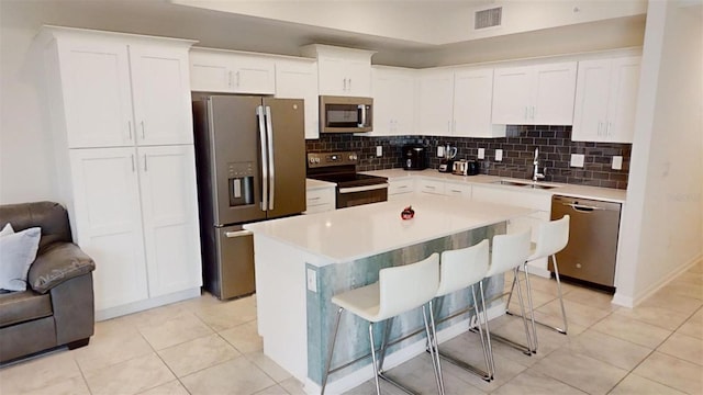 kitchen featuring sink, a breakfast bar, appliances with stainless steel finishes, a center island, and white cabinets