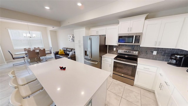 kitchen with white cabinetry, appliances with stainless steel finishes, light tile patterned flooring, and decorative backsplash