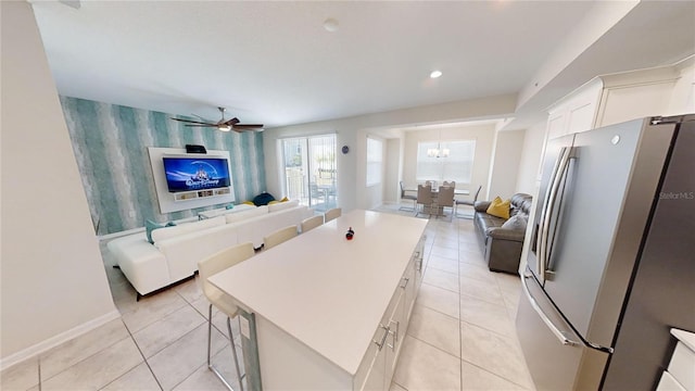 kitchen featuring a kitchen island, white cabinetry, a breakfast bar area, stainless steel fridge, and light tile patterned floors