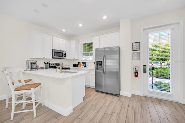 kitchen with white cabinets, stainless steel appliances, sink, and kitchen peninsula