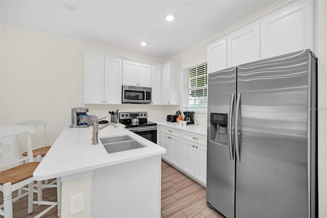 kitchen featuring white cabinets, stainless steel appliances, sink, and kitchen peninsula