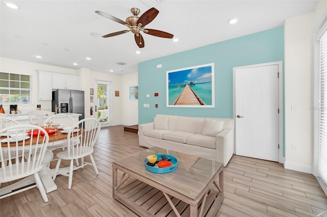 living room with light hardwood / wood-style floors, ceiling fan, and a wealth of natural light