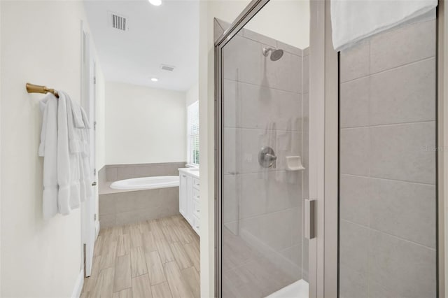 bathroom with vanity and shower with separate bathtub