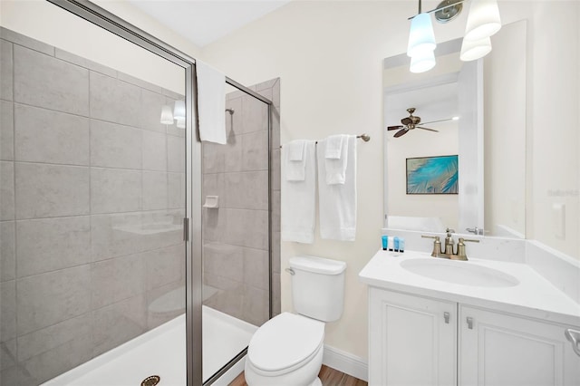 bathroom with a shower with shower door, vanity, ceiling fan, and toilet