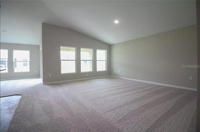 carpeted spare room with vaulted ceiling