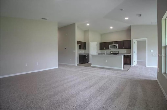 unfurnished living room featuring high vaulted ceiling and light carpet