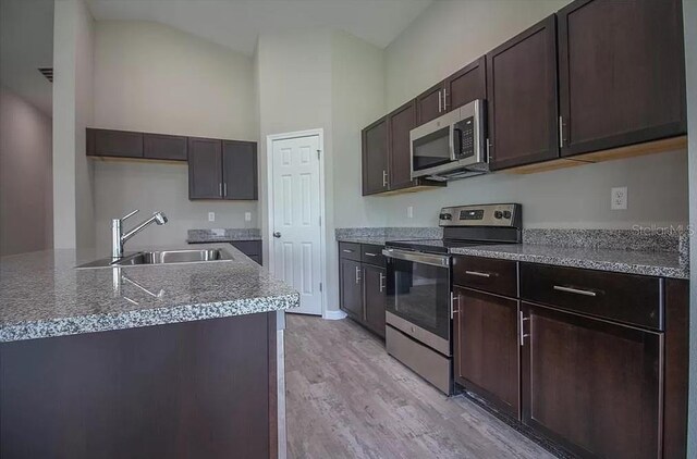 kitchen featuring dark brown cabinetry, sink, stainless steel appliances, and light hardwood / wood-style floors