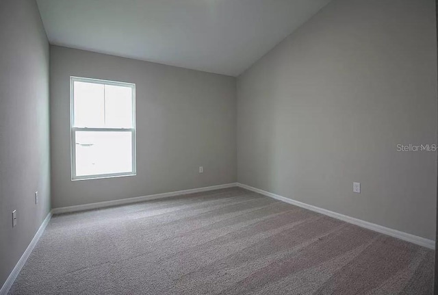 spare room with lofted ceiling and carpet flooring