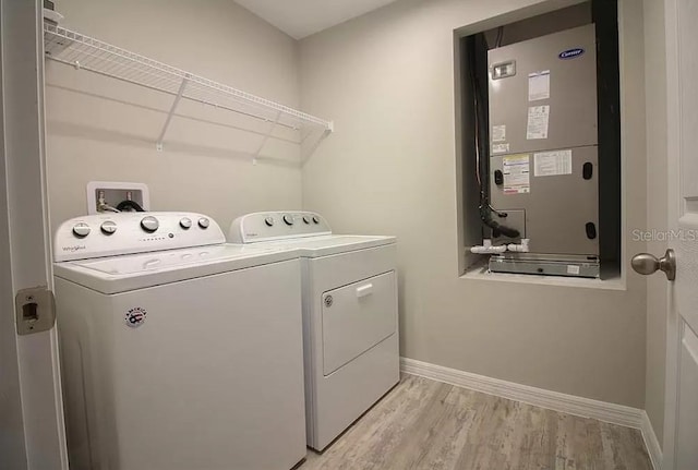 clothes washing area featuring heating unit, light hardwood / wood-style floors, and washer and dryer