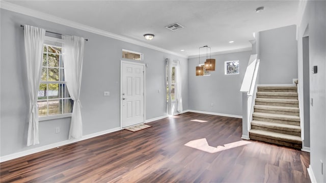 entrance foyer with an inviting chandelier, ornamental molding, and dark hardwood / wood-style flooring