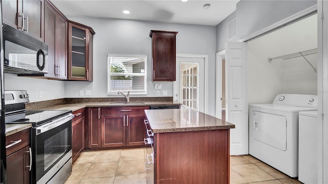 kitchen with sink, separate washer and dryer, a center island, stainless steel electric range, and light tile patterned floors