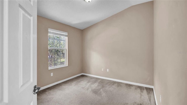 carpeted spare room featuring lofted ceiling and a textured ceiling