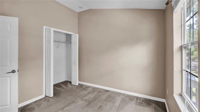 unfurnished bedroom with light colored carpet, lofted ceiling, and a closet