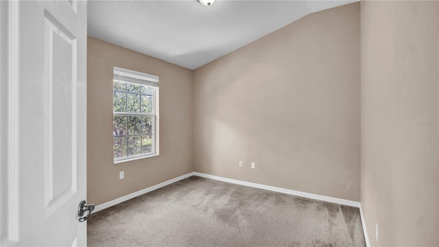 empty room featuring lofted ceiling and carpet flooring